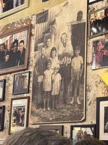 Vintage black-and-white family photograph displayed among framed photos on the wall at Emilio’s Ballato Italian restaurant in NoHo, New York City, representing generations of families and shared history.