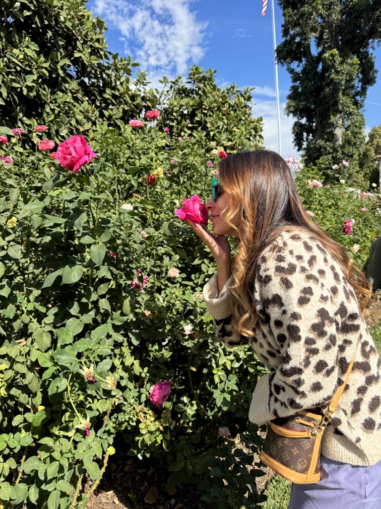 Danielle Alvarez Greer pausing to smell pink roses at the Huntington Library and Botanical Gardens in Pasadena, California.