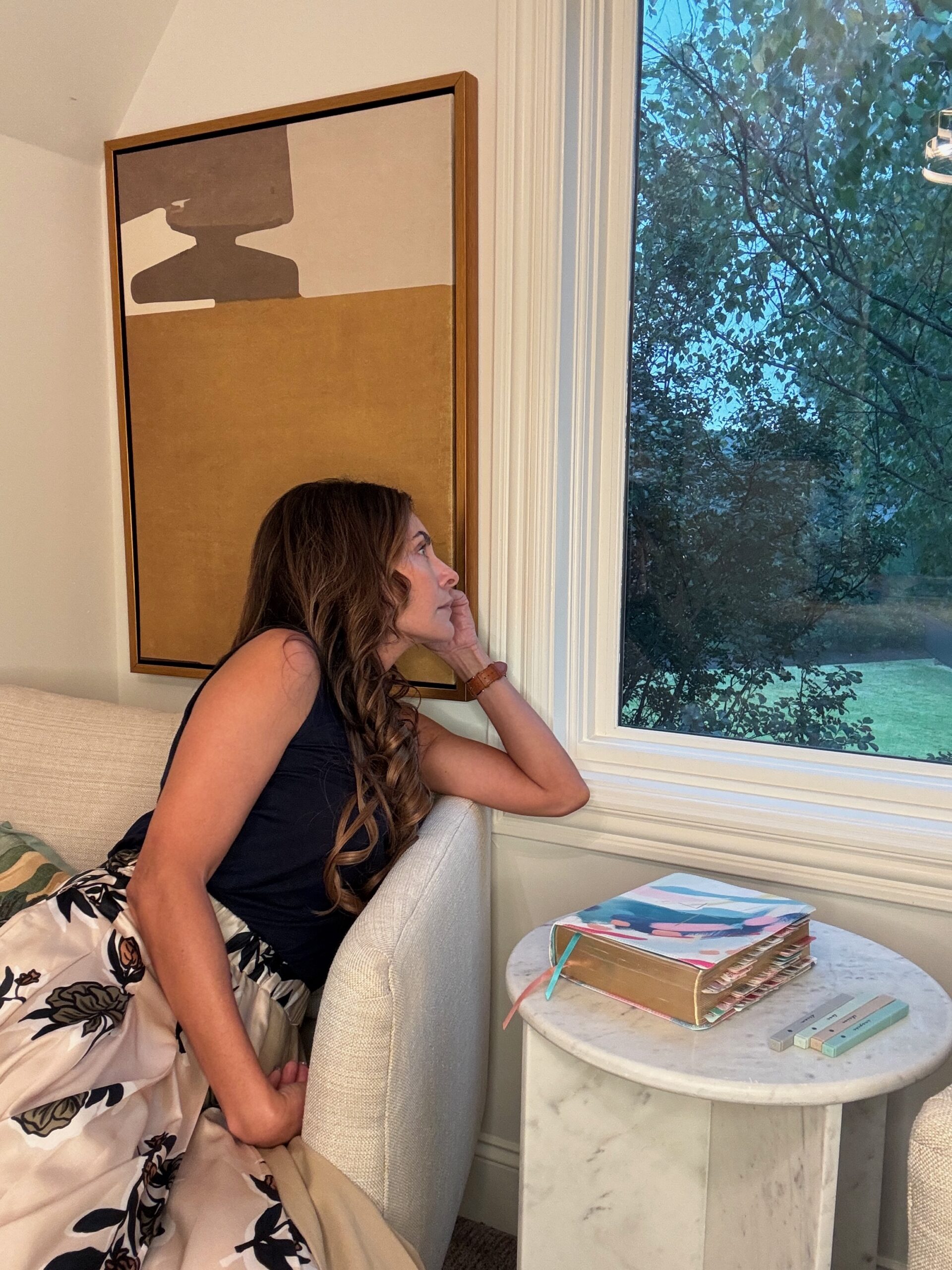 Woman sitting quietly by window reflecting with Bible, illustrating spiritual reflection and awareness in Ezekiel 9