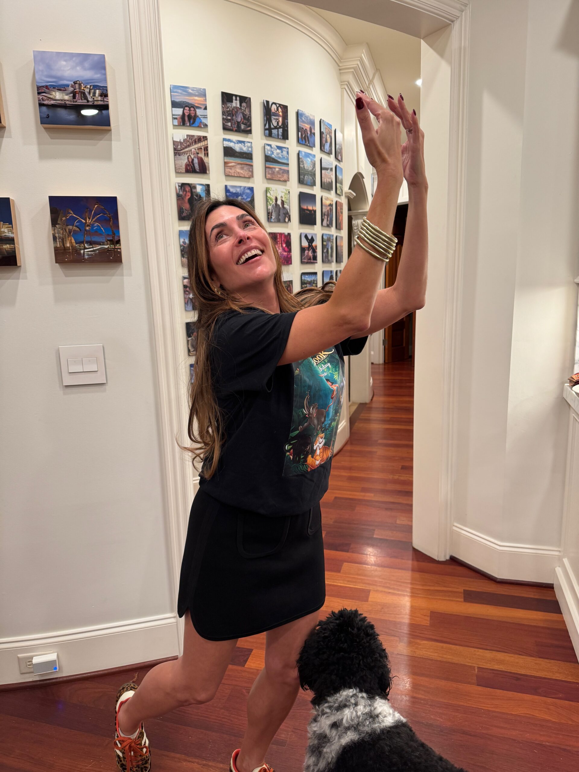 Danielle Alvarez Greer laughing and playfully raising her arms in her kitchen at home, illustrating the everyday pressure of overfunctioning in marriage.