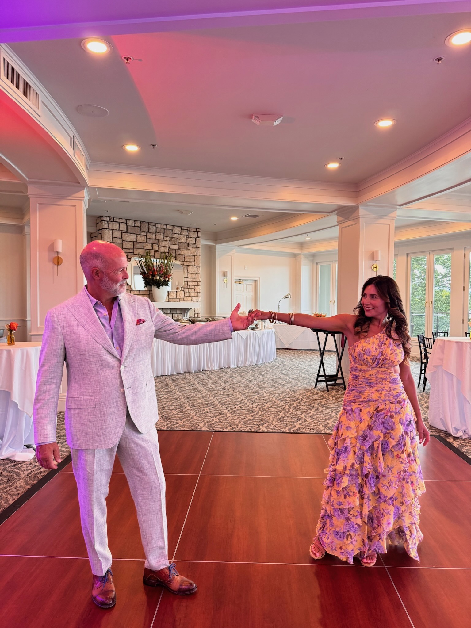 Married couple reaching toward one another and holding hands on a dance floor before a 50th birthday celebration, illustrating connection, marriage repair, and emotional intimacy.
